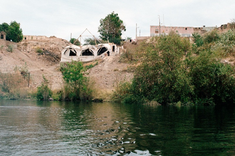 Approaching Heissa by boat: the domes of Tekkeya above the green riverbank