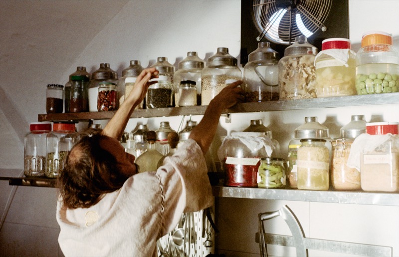 George reaching for jars of herbs, seeds and spices on the kitchen shelves