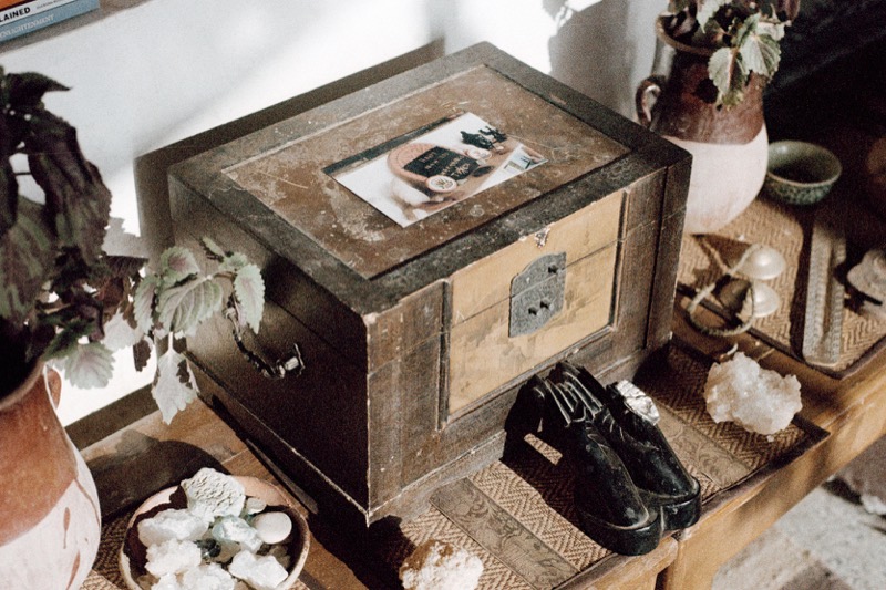 A carved wooden chest among crystals, books and plants