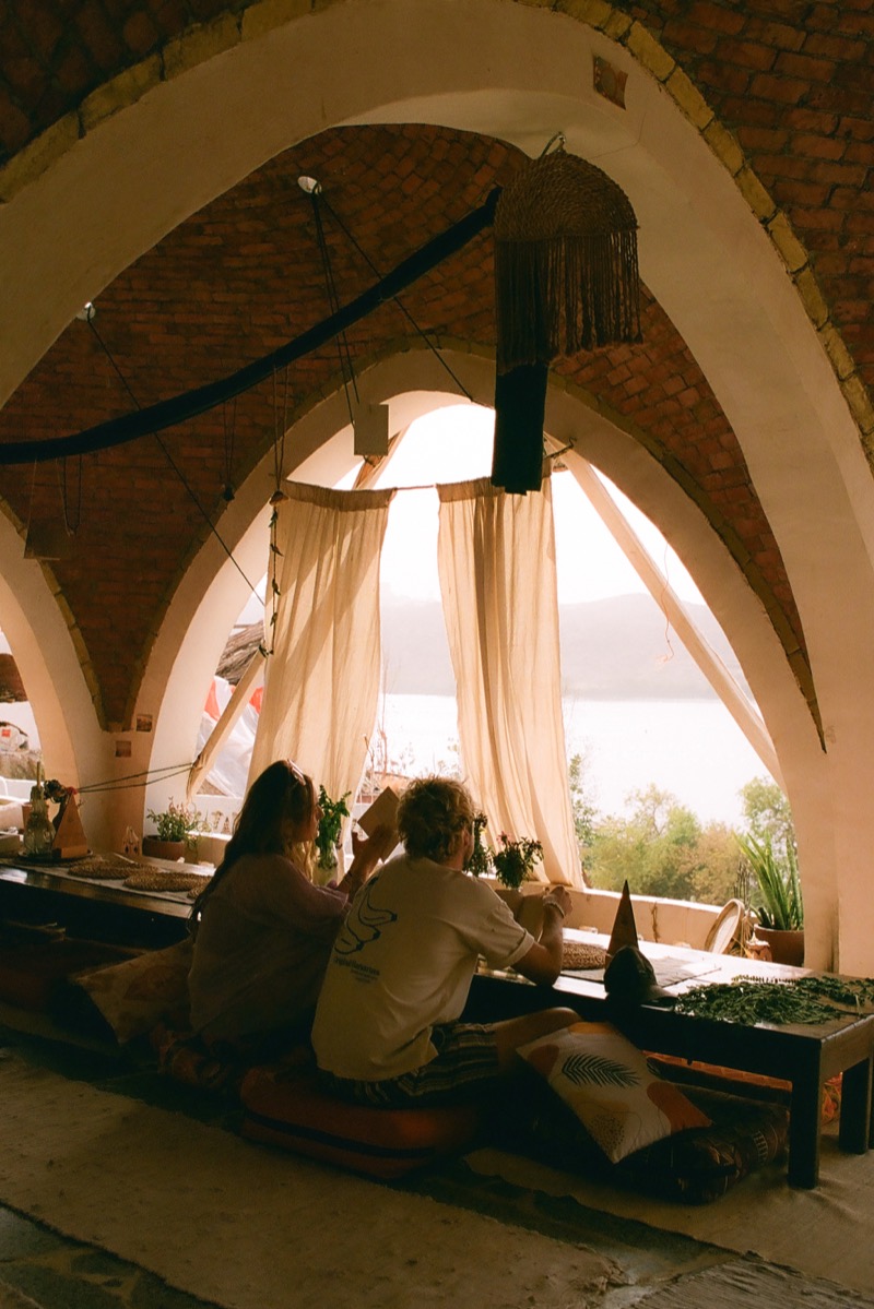Guests at lunch under the brick arches, the river beyond the curtains