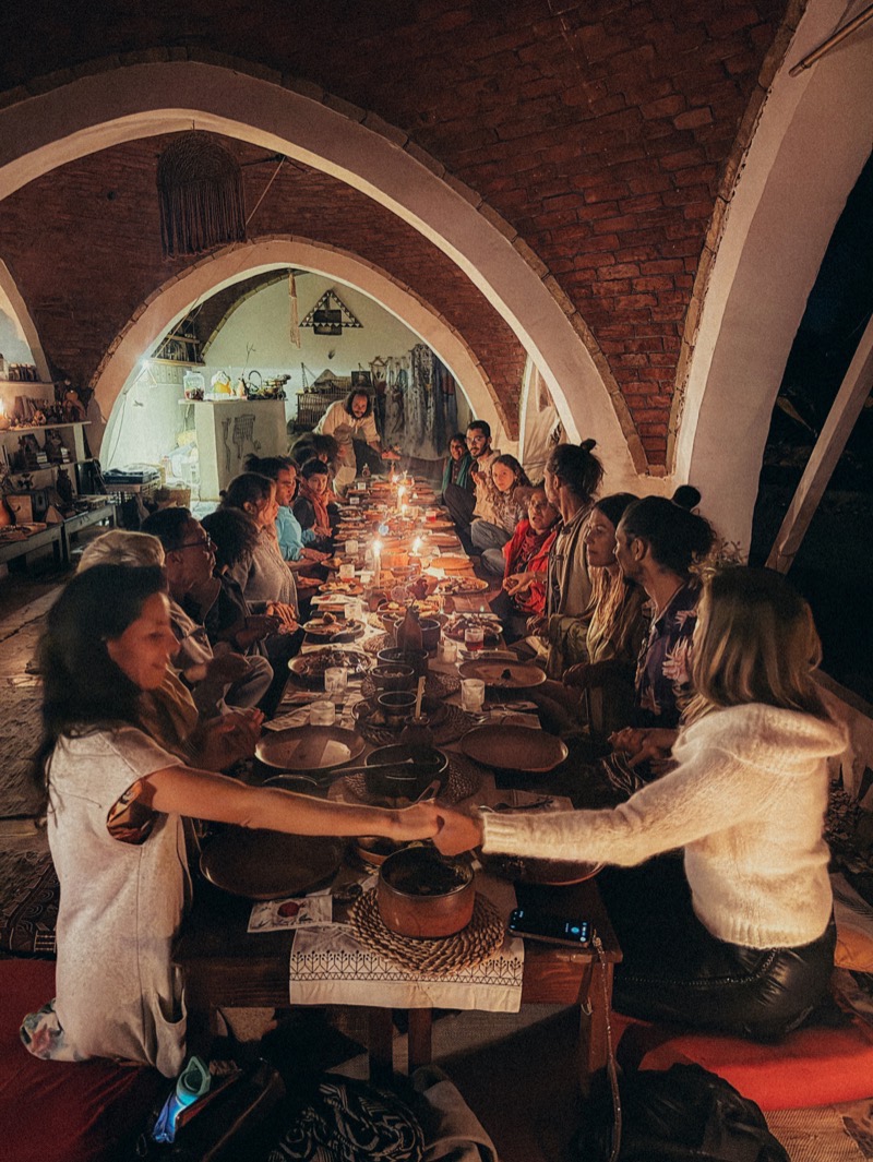 A long candle-lit supper, guests joining hands around the table
