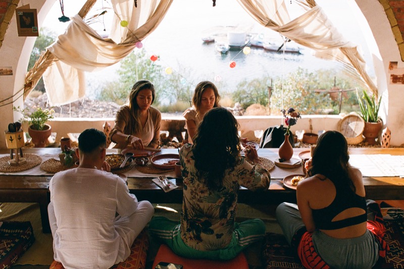 Guests sharing a meal at the low table, the Nile through the open window